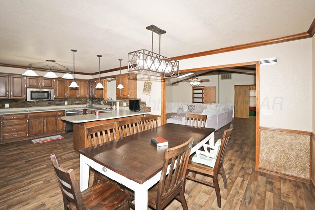 1005 Bennett Dr, Dumas, TX 79029 - dining space featuring a ceiling fan, dark wood-type flooring, crown molding, and a textured ceiling