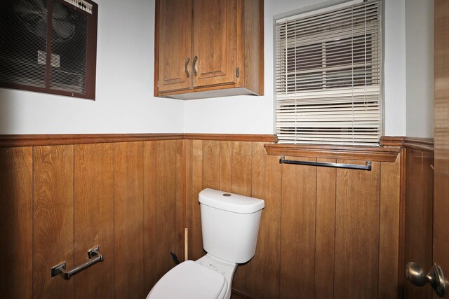 bathroom with a wainscoted wall, toilet, and visible vents