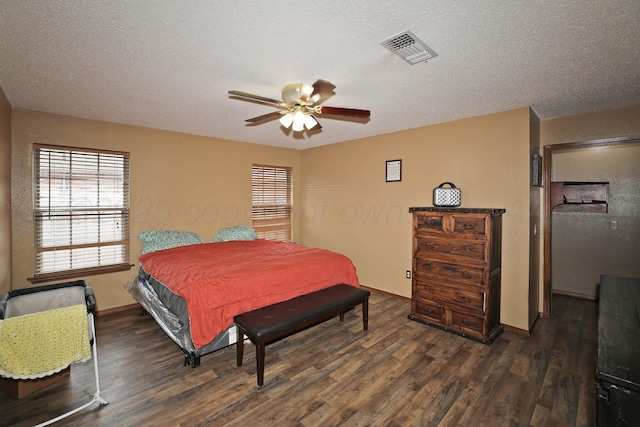 bedroom with baseboards, a textured ceiling, wood finished floors, and visible vents
