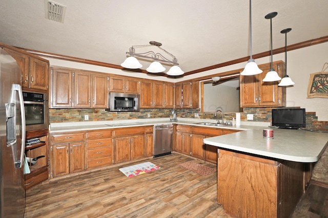 1005 Bennett Dr, Dumas, TX 79029 - kitchen featuring a sink, stainless steel appliances, a peninsula, brown cabinetry, and backsplash