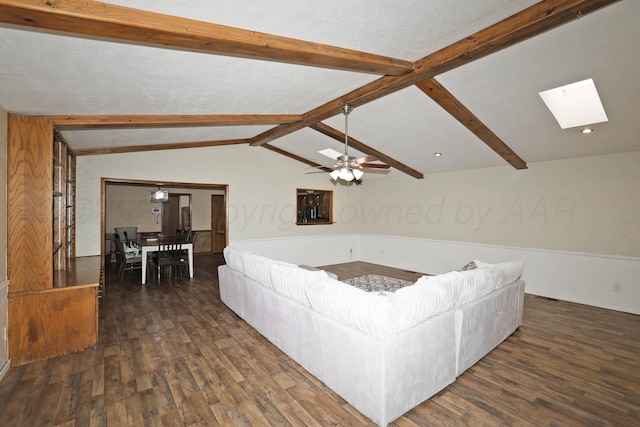 living area featuring vaulted ceiling with skylight, ceiling fan, and dark wood-style flooring