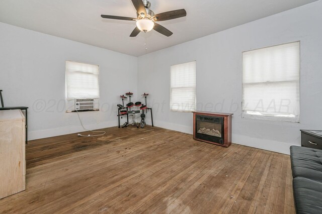300 E 4th St, Clarendon, TX 79226 - living area featuring a ceiling fan, hardwood / wood-style floors, a glass covered fireplace, and cooling unit