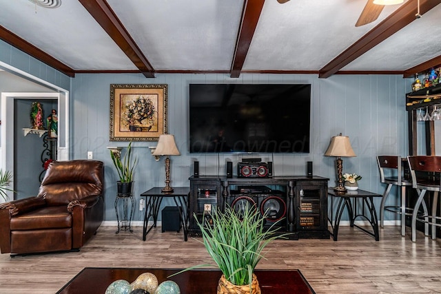 living area featuring baseboards, beam ceiling, a ceiling fan, and wood finished floors