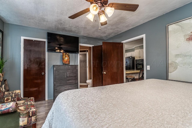 bedroom featuring a ceiling fan, freestanding refrigerator, a textured ceiling, and wood finished floors