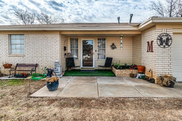 doorway to property with a patio area and brick siding