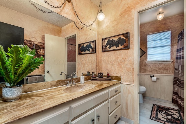 full bath with a wainscoted wall, vanity, and toilet