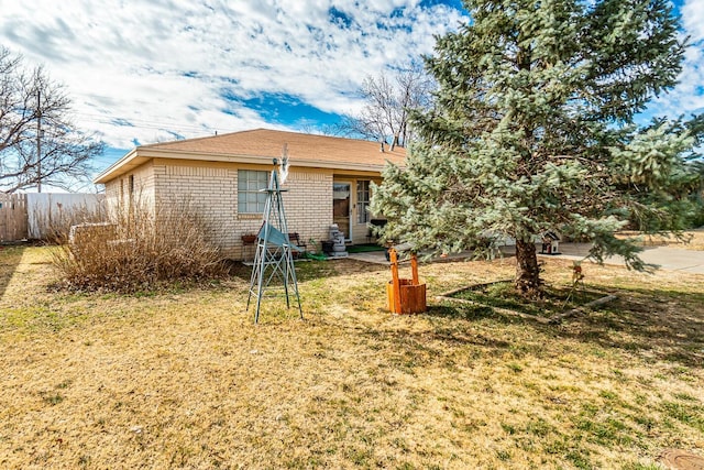 exterior space with brick siding, a front yard, and fence