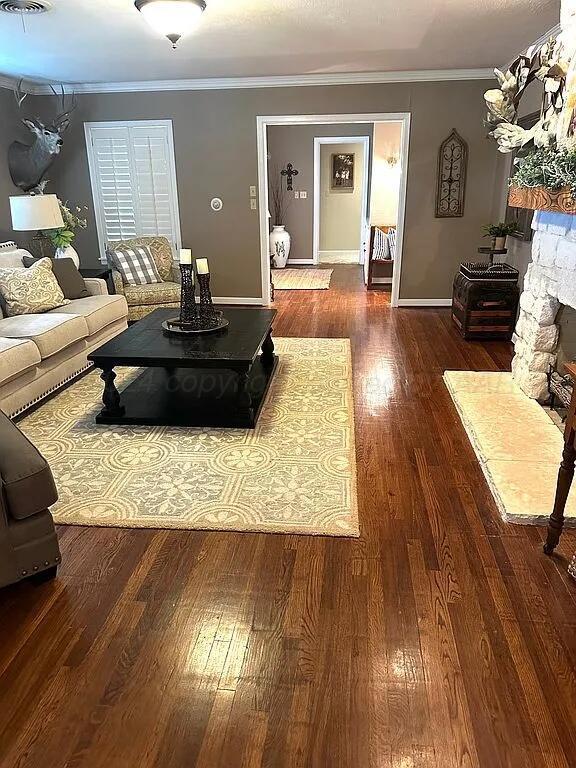 living room with a fireplace, crown molding, and dark wood-type flooring