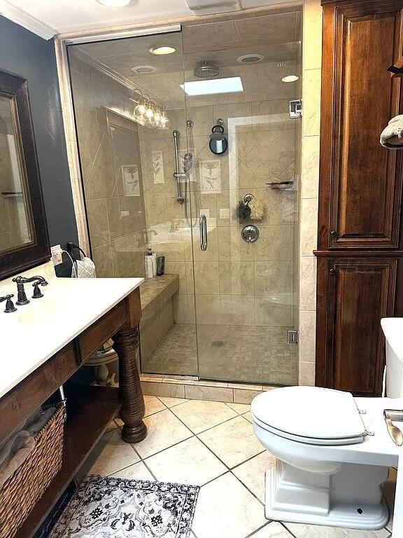 bathroom featuring tile patterned flooring, vanity, a shower with shower door, and toilet