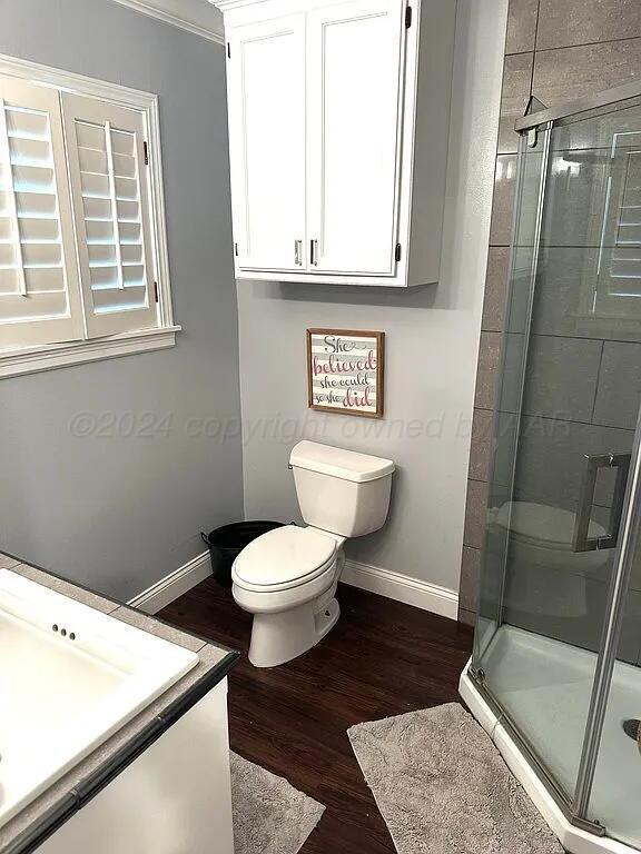 bathroom with crown molding, toilet, vanity, a shower with shower door, and hardwood / wood-style flooring