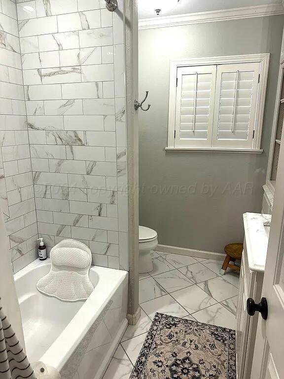 bathroom featuring toilet, tiled shower / bath, and crown molding