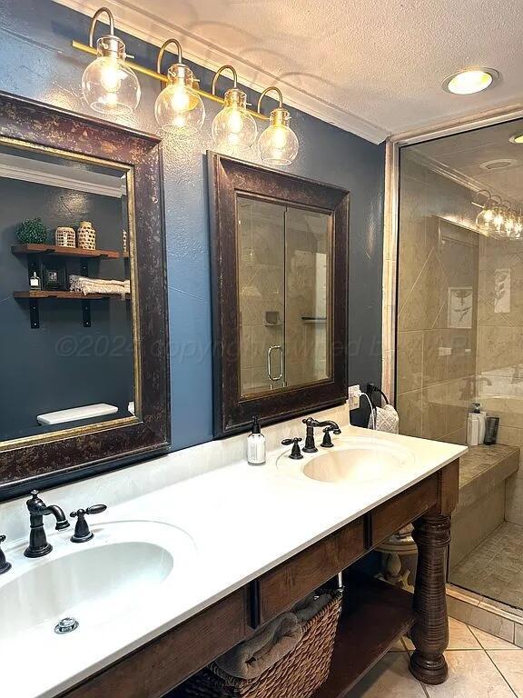 bathroom with tile patterned floors, vanity, a shower with door, and a textured ceiling