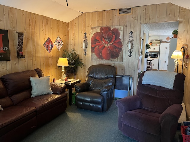 carpeted living room with wood walls and vaulted ceiling