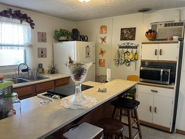 kitchen with white cabinets, a textured ceiling, sink, and white refrigerator