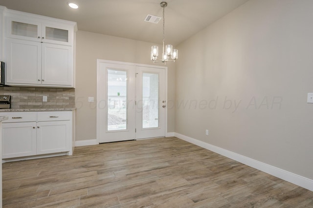 unfurnished dining area with a chandelier, light hardwood / wood-style floors, and lofted ceiling