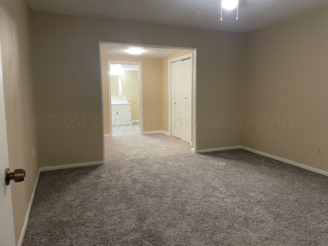 unfurnished room with carpet and a textured ceiling