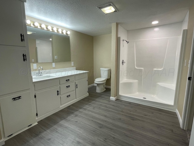 bathroom featuring walk in shower, toilet, a textured ceiling, vanity, and hardwood / wood-style flooring