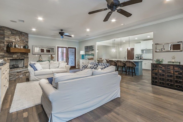 living room featuring a stone fireplace, ornamental molding, ceiling fan, and dark hardwood / wood-style floors