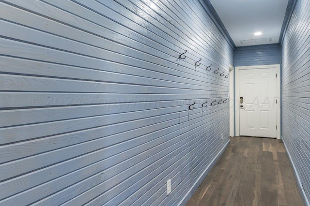 corridor with wood walls and dark wood-type flooring