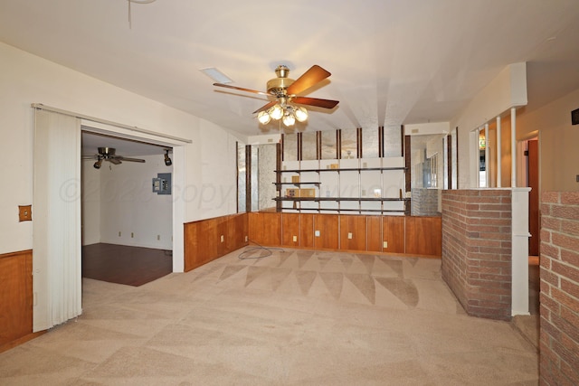 unfurnished room with ceiling fan, light carpet, and wood walls