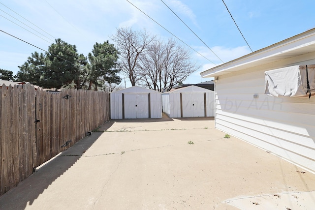 view of yard featuring a storage unit, fence, a patio area, and an outdoor structure