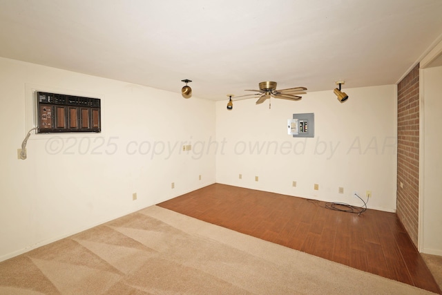 carpeted spare room featuring ceiling fan, a wall mounted AC, wood finished floors, and electric panel