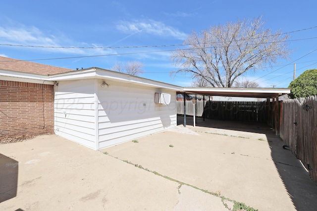 garage with fence, driveway, and a detached carport