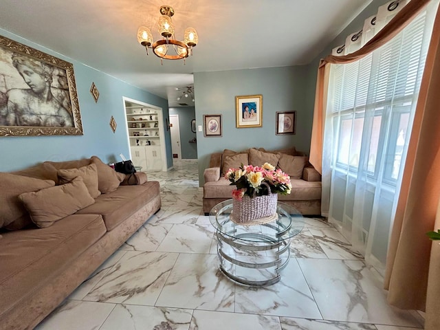 living area with built in features, marble finish floor, and a notable chandelier