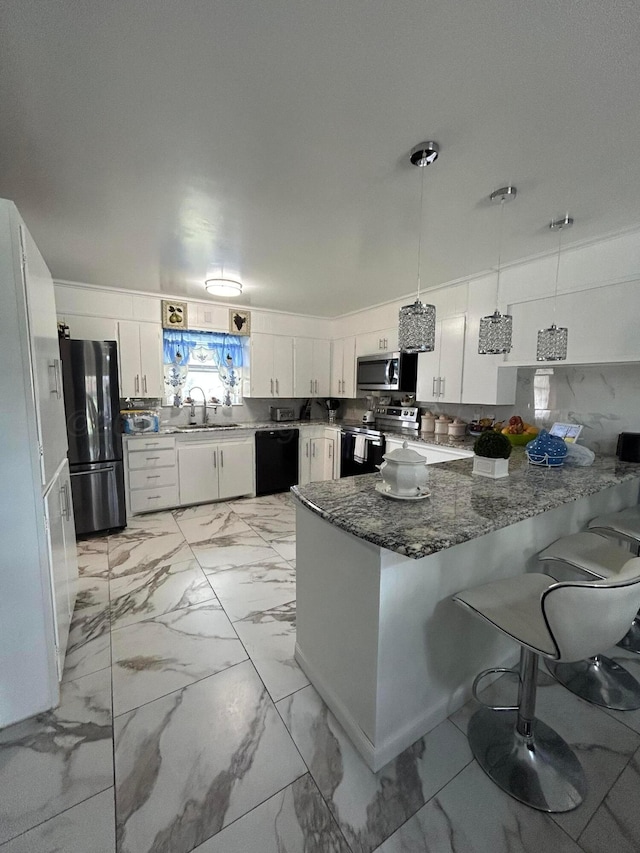 kitchen featuring appliances with stainless steel finishes, a sink, marble finish floor, a peninsula, and white cabinetry