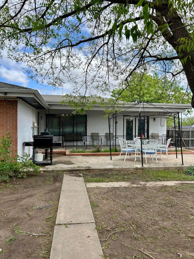 rear view of house featuring brick siding, a patio area, and fence