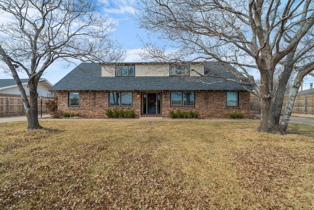 view of front of home featuring fence, a front lawn, and brick siding