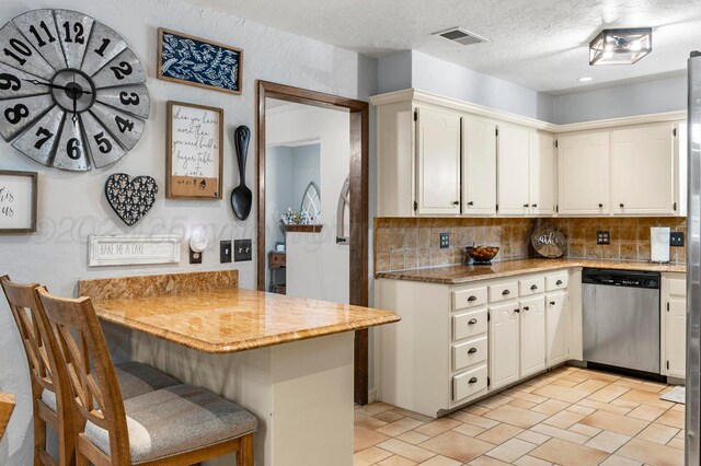 2428 N Fir St, Pampa, TX 79065 - kitchen with dishwasher, backsplash, a kitchen breakfast bar, a peninsula, and a textured ceiling