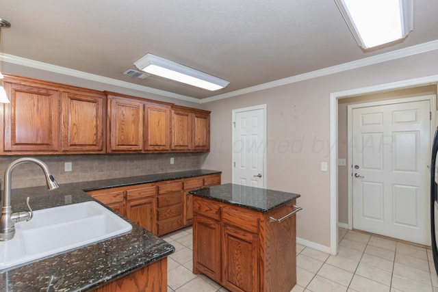 6703 Mosley St, Amarillo, TX 79119 - kitchen featuring a sink, brown cabinets, decorative backsplash, light tile patterned floors, and crown molding