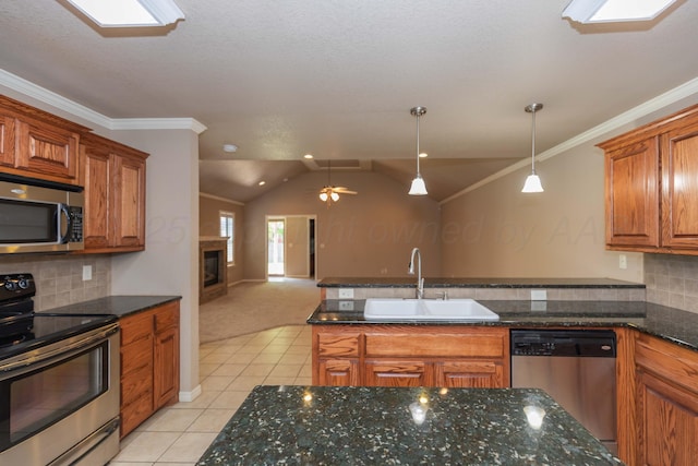 6703 Mosley St, Amarillo, TX 79119 - kitchen featuring stainless steel appliances, a sink, light tile patterned floors, brown cabinets, and vaulted ceiling