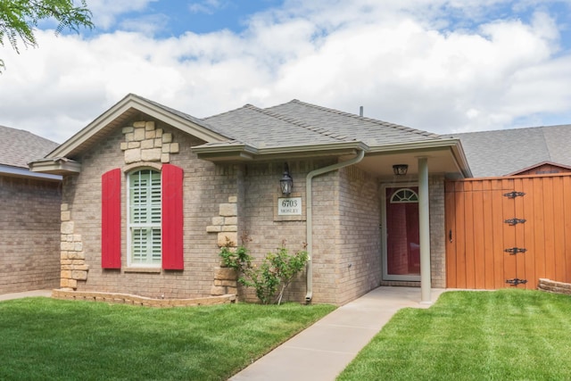 6703 Mosley St, Amarillo, TX 79119 - view of front of home with a shingled roof, a front lawn, brick siding, and a gate