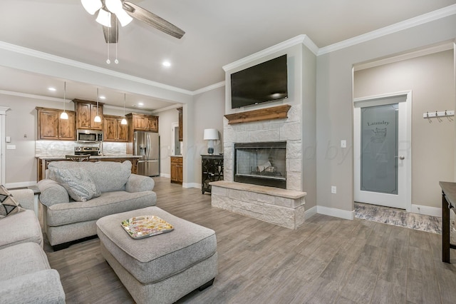 7611 Crestline Dr, Amarillo, TX 79119 - living room featuring a ceiling fan, light wood finished floors, a stone fireplace, crown molding, and recessed lighting