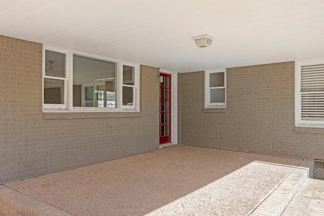 doorway to property featuring brick siding and a patio area