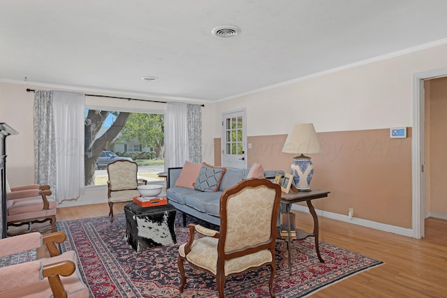 living room with ornamental molding, light wood-type flooring, and baseboards