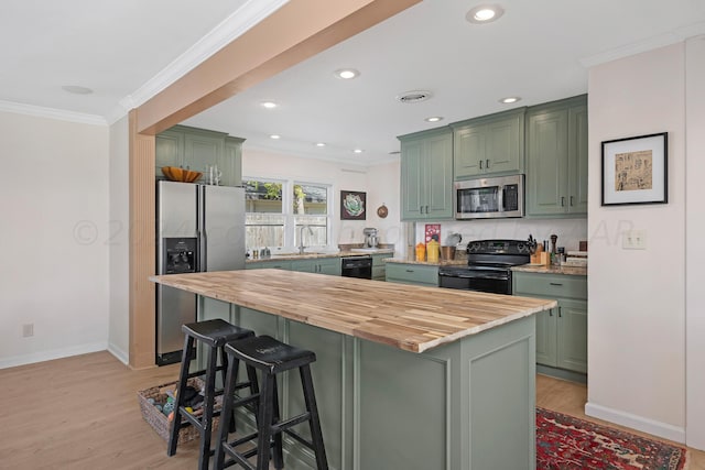 kitchen featuring black appliances, green cabinets, wood counters, a sink, and crown molding
