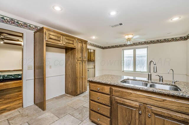 7502 Tripp Ave, Amarillo, TX 79121 - kitchen with a ceiling fan, light stone countertops, stone tile floors, brown cabinets, and recessed lighting