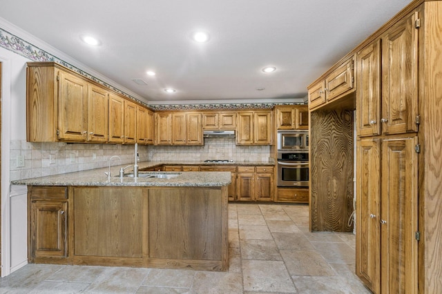 7502 Tripp Ave, Amarillo, TX 79121 - kitchen with stainless steel appliances, a peninsula, under cabinet range hood, decorative backsplash, and light stone counters