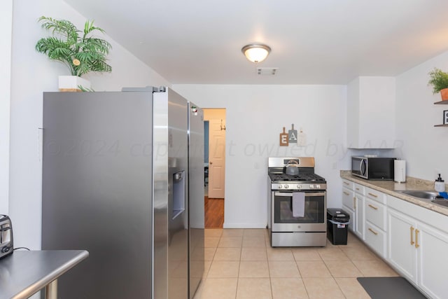3002 S Polk St, Amarillo, TX 79109 - kitchen featuring stainless steel appliances, white cabinets, light tile patterned floors, a sink, and light countertops
