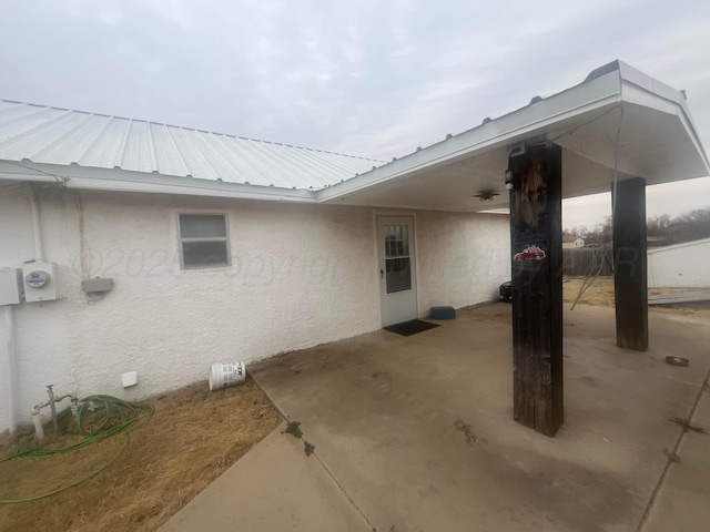 view of side of home with metal roof, a patio, and stucco siding