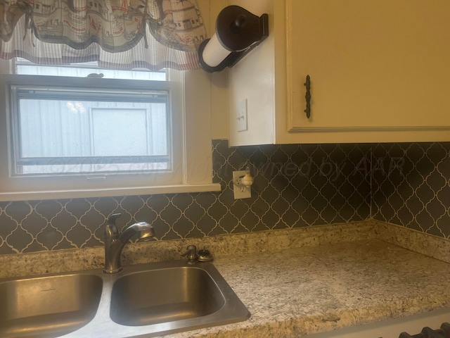 kitchen featuring light countertops, decorative backsplash, a sink, and white cabinets