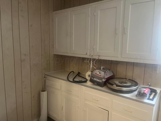 interior space featuring light countertops, wooden walls, and white cabinets