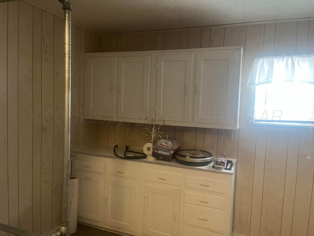 kitchen featuring wooden walls, white cabinetry, and light countertops