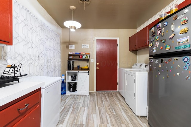 clothes washing area featuring light wood finished floors, laundry area, and independent washer and dryer