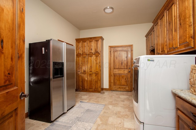 clothes washing area featuring washer / clothes dryer, baseboards, stone finish floor, and cabinet space
