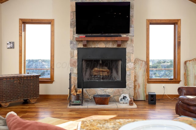 living room with a fireplace, baseboards, and wood-type flooring