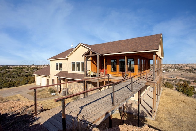 back of house featuring concrete driveway and roof with shingles